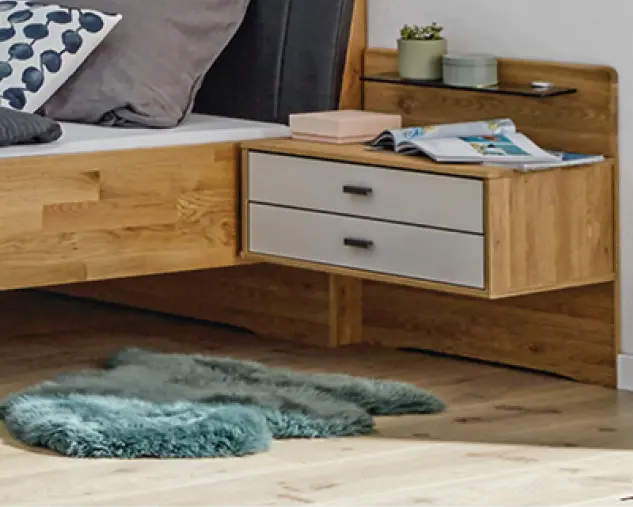 Schwebender Nachttisch aus Massivholz mit zwei Schubladen neben einem Holzbett. Funktionale Schlafzimmermöbel im modernen Design mit natürlicher Holzoptik, klaren Formen und praktischer Ablagefläche.